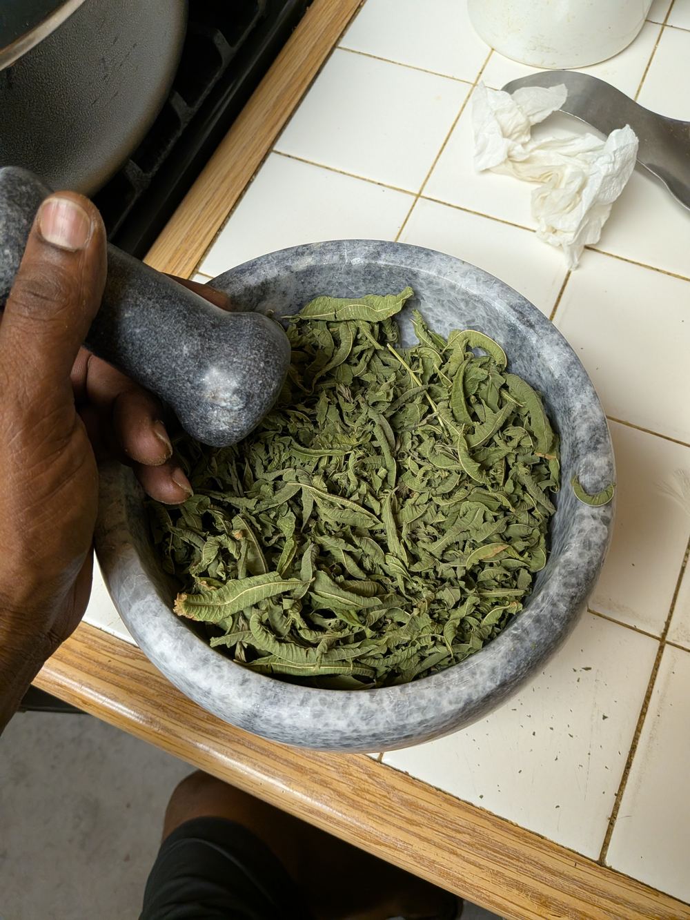 Grinding dried homegrown herbs by hand with a mortar and pestle